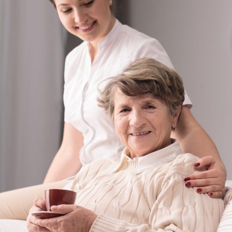 Young female caregiver taking care of older woman